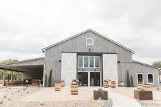 a barn with several barrels in front of it and a walkway leading up to the building