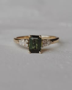 a green and white diamond ring sitting on top of a table