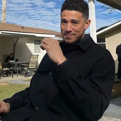 a man standing in front of a house with his hand on his chin and looking at the camera