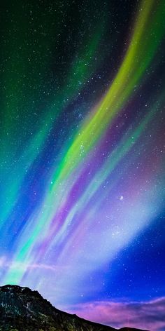 an aurora bore is seen in the night sky over a mountain range with green and purple lights