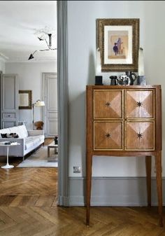 a wooden cabinet sitting on top of a hard wood floor next to a white couch