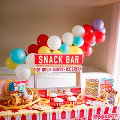 a snack bar set up with balloons and snacks