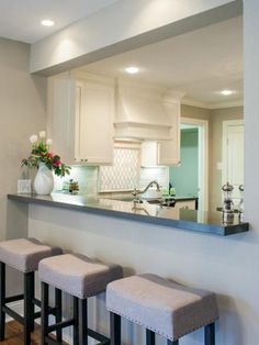 three stools sit in front of a kitchen counter with flowers on the counter top