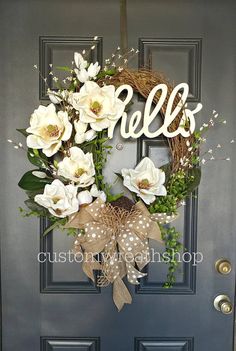 a wreath with the word hello spelled on it and white flowers in front of a blue door