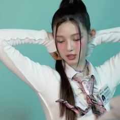 a girl with long hair wearing a white shirt and tie holding her hands behind her head