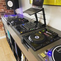 there is a laptop on top of the dj's desk and two decks of turntables