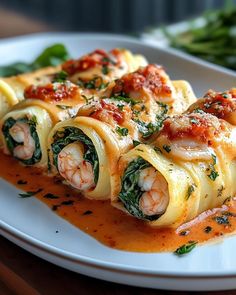 a white plate topped with pasta covered in sauce and garnished with spinach