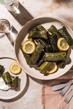 a bowl filled with lemons and wrapped in leaves next to silverware on top of a table