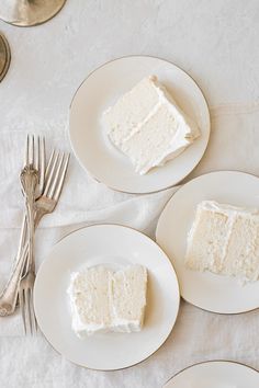 three white plates with slices of cake on them and silverware next to each other