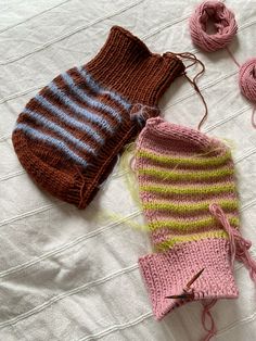 two knitted hats and one crochet hat on a bed