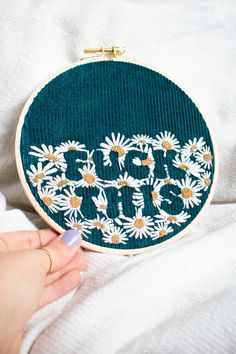 someone is stitching the word jesus in daisies on a green embroidered wall hanging