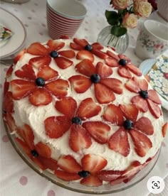 a cake with strawberries and blueberries on it sitting on top of a table