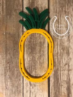 a yellow and green pineapple shaped object sitting on top of a wooden floor next to a hook