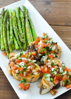 grilled chicken with asparagus and tomato relish on a white platter