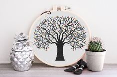 a cross - stitch tree with colorful leaves on it next to a potted cactus