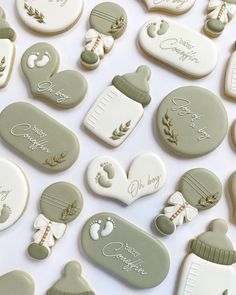 many decorated cookies are displayed on a white tablecloth with baby's footprints and name tags