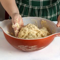 a person mixing dough in a red bowl