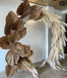 a sculpture made out of straw and feathers in a room with wood flooring on the walls