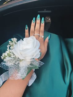 a woman's hand holding a white rose with green and white decorations on it