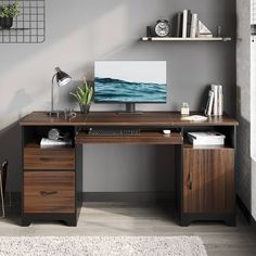 a desk with a computer on it in front of a gray wall and white rug