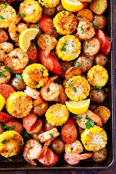 a pan filled with shrimp, potatoes and lemons