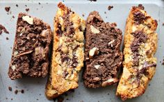 four pieces of chocolate and almond bread on a baking sheet with crumbs all over it