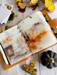 an open planner book sitting on top of a table next to fall leaves and other decorations