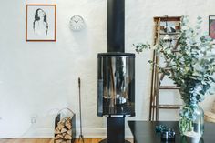 a living room with a wood burning stove next to a table and chair in front of a clock