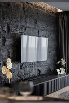 a living room with black stone walls and a flat screen tv mounted on the wall