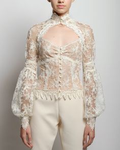 A sheer lace blouse with a high neck and hand placed embroidery at collar and cuff closures. The Eliza blouse features a fitted empire cut along with front décolletage and raglan romantic billow sleeves. French lace lined with nude color mesh Delicate satin button closure for collar, cuffs and front Dry clean only Each piece is made to order and handcrafted in our atelier. Slight variations may occur as each piece is unique. Romantic Blouses, High Neck Blouse, Unique Blouse, Lace Outfit, French Lace, Dress Cuts, Dream Clothes, Lace Blouse, Sheer Lace