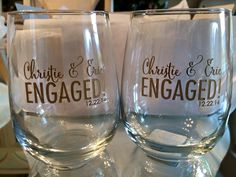 two wine glasses sitting on top of a table with the names engaged printed on them