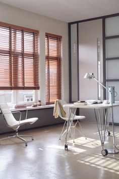 a white desk and chair in front of windows with wooden blinds on them, next to a window with shutters