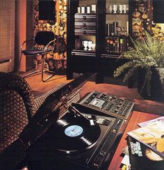 a record player sitting on top of a table in front of a book shelf filled with records