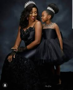 two women in black dresses and tiaras pose for the camera