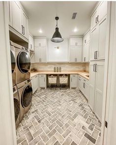 an empty laundry room with white cabinets and tile flooring