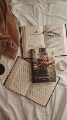 an open book sitting on top of a bed next to a cup of coffee