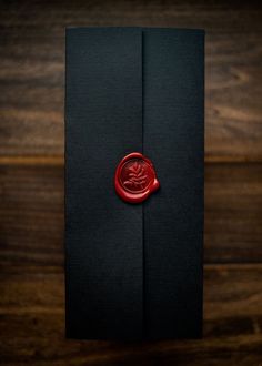 a waxed seal sitting on top of a black piece of paper next to a wooden table