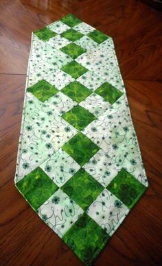 a green and white patchwork table runner on a wooden floor with wood floors in the background