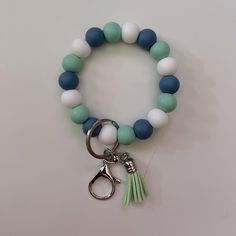 a green and white bracelet with a pair of scissors hanging from it's end