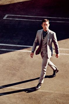 a man in a suit walking across a tennis court