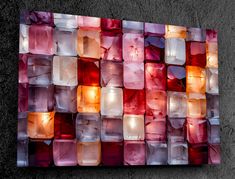 an abstract piece of art made out of glass cubes on concrete wall with light shining through