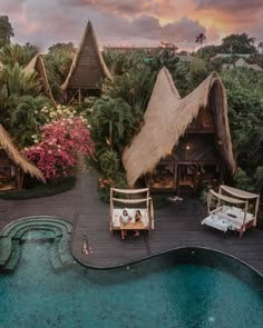 an aerial view of a resort pool with thatched roof huts