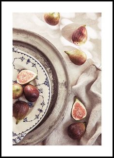 figs on a plate and some other fruit sitting on a table cloth next to each other