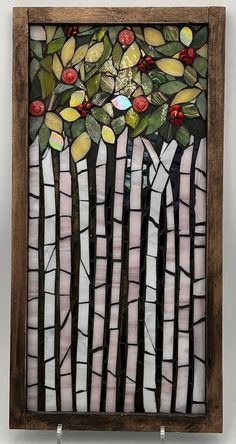 a stained glass window with trees and berries on it's side, in a wooden frame