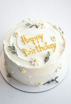 a birthday cake with white frosting and yellow flowers on the top that says happy birthday