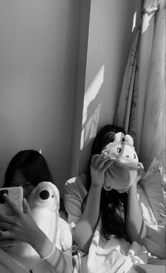 a woman laying in bed holding a stuffed animal next to her face and covering her eyes