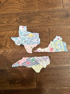 three pieces of paper cut out to look like the state of texas on a wood floor