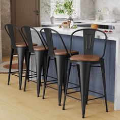 four black metal bar stools sitting in front of a kitchen island