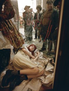 a woman laying on the ground in front of a group of people standing and sitting