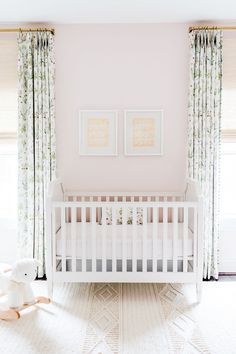 a white crib in a room with curtains and pictures on the wall above it